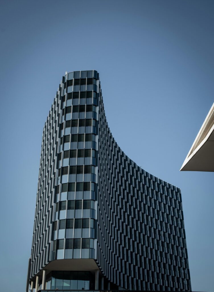 A striking modern building with a unique curved facade against a clear blue sky, showcasing contemporary architecture.